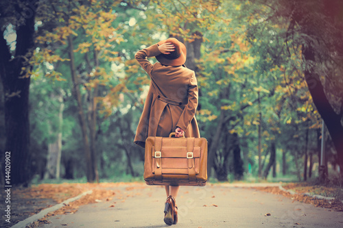 photo of beautiful young woman with suitcase on the wonderful autumn park background photo