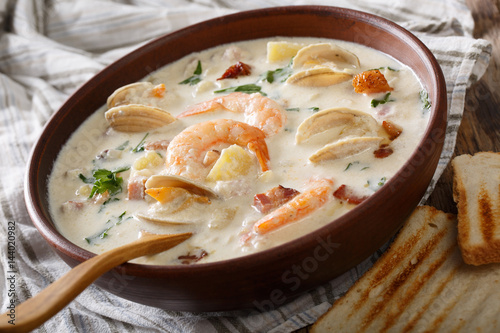 Delicious clam chowder soup with shellfish and bacon close-up on a in a bowl. horizontal photo