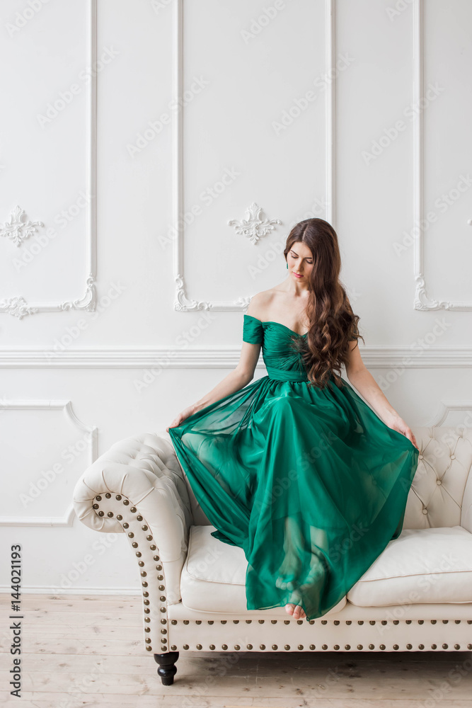 beautiful girl in a long emerald green dress sitting on a leather couch ...
