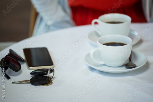 Coffee cups and personal accessories on cafe table
