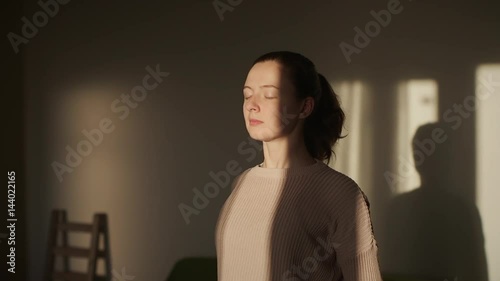 Young fit woman warming up shoulders at home slow motion. sunset