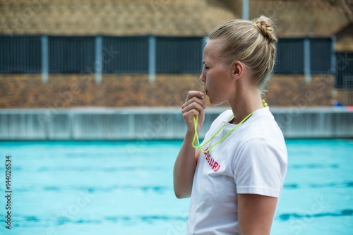 Foto Female lifeguard whistling at poolside