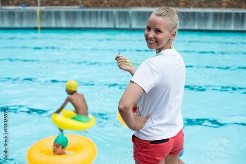 Photos Confident female lifeguard holding whistle at poolside