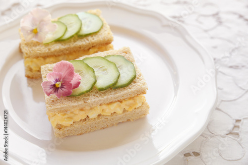 Egg and cucumber afternoon tea sandwiches with edible flowers, toning
