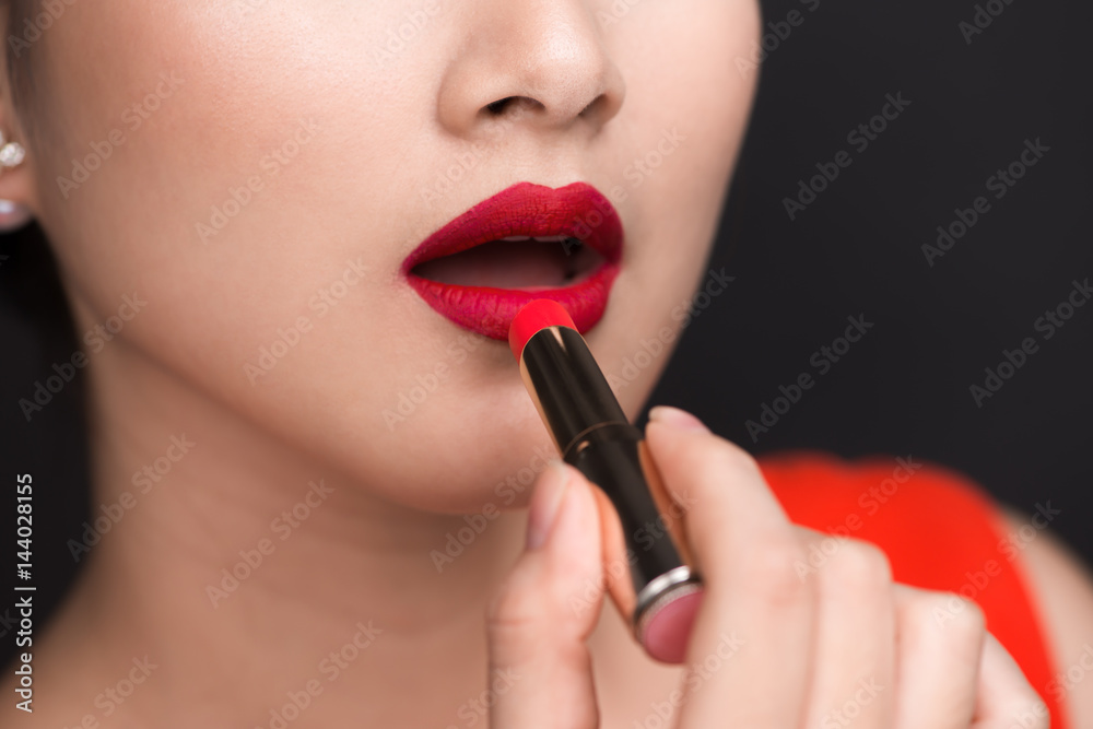 Professional Make-up. Attractive asian model applying red lipstick.