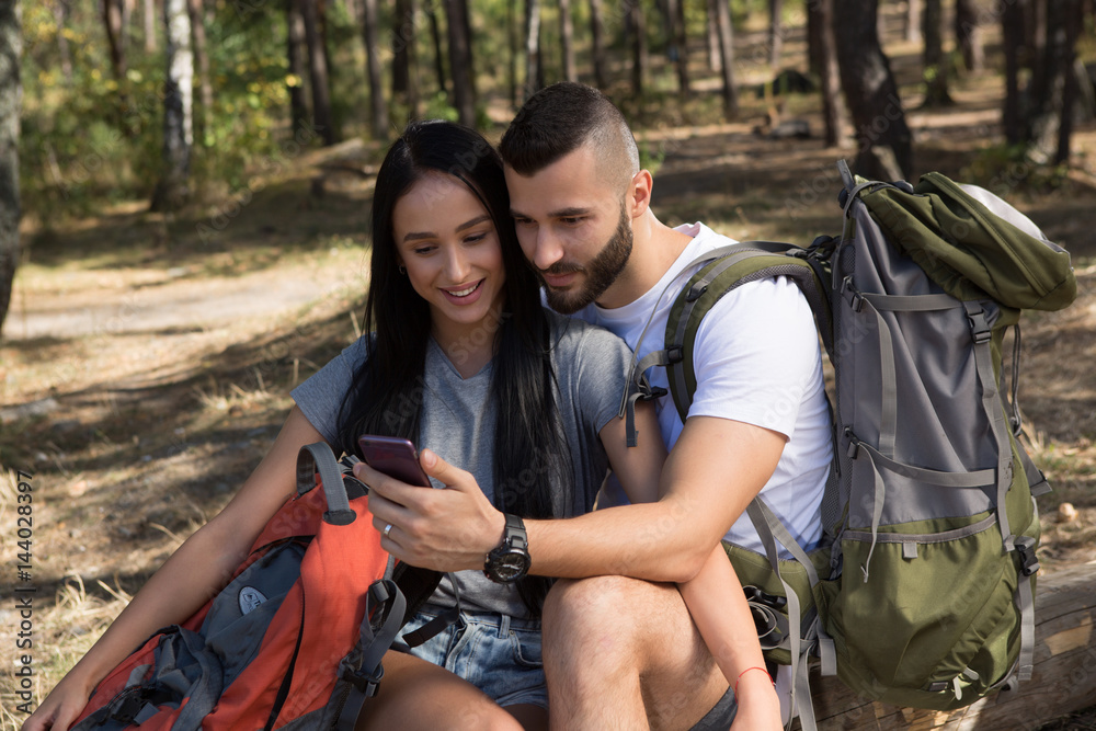 Young couple using smartphone while hiking