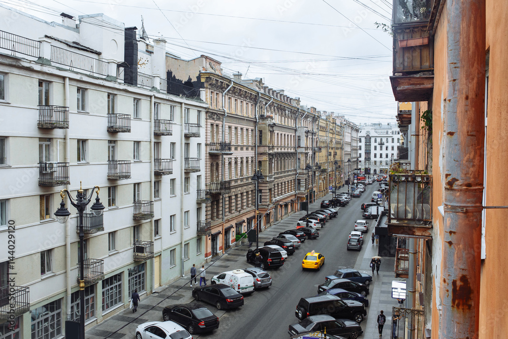 Obraz premium Street in town with parked cars in the middle goes yellow taxi