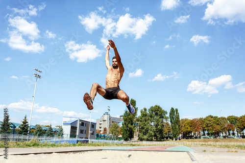 Male athlete performing a long jump photo