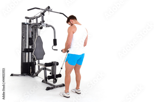 Athlete (bodybuilder) with is doing exercise on for certain groups of muscles in a simulator block. Isolated on white background.