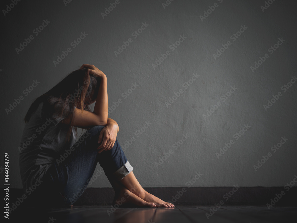 sad woman hug her knee and cry. Sad woman sitting alone in a empty room.