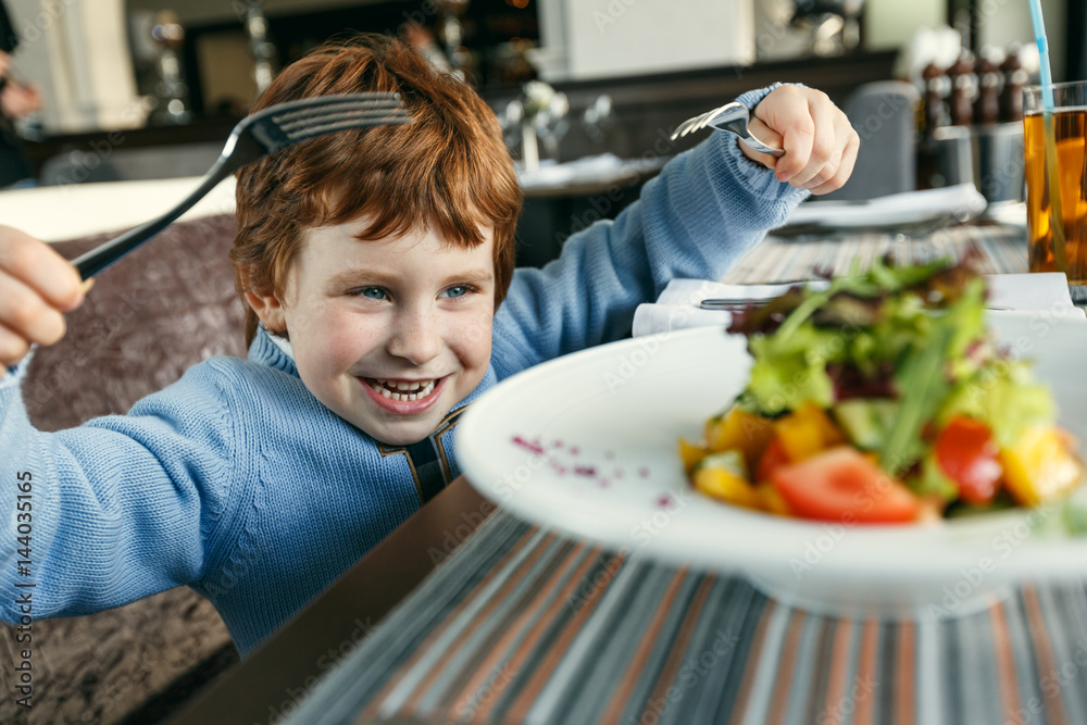 Red haired boy with forks eating salad Red haired boy with forks eating salad