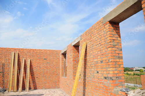 House construction concept.  Interior of a unfinished red brick house under construction. Closeup on windows hole construction with concrete lintel. photo