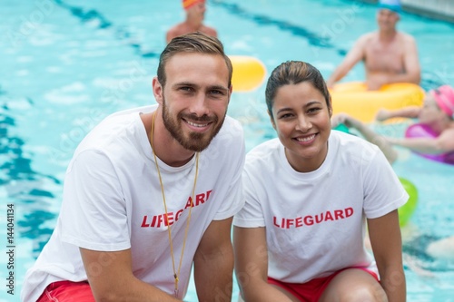 Male and female lifeguards crouching at poolside photo
