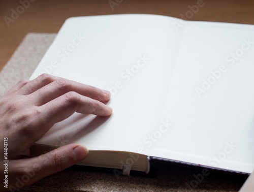 Female hands holding diary on the wooden desk. With space for text