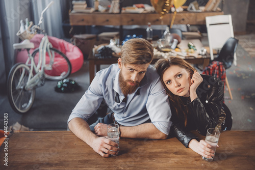 man and woman with hangover with medicines in messy room after party