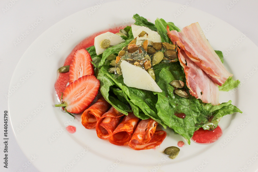 Mix of hot sausages with bacon on a cushion of lettuce leaves, in a duet with parmesan and strawberries, garnished with pumpkin seeds, dressed with raspberry sauce Mix of hot sausages with bacon on a cushion of lettuce leaves, in a duet with parmesan and strawberries, garnished with pumpkin seeds, dressed with raspberry sauce