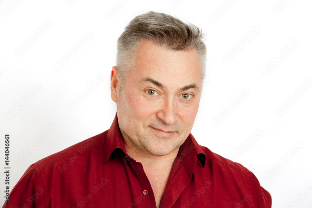 A gray-haired man in a red shirt smiling on a white background A gray-haired man in a red shirt smiling on a white background