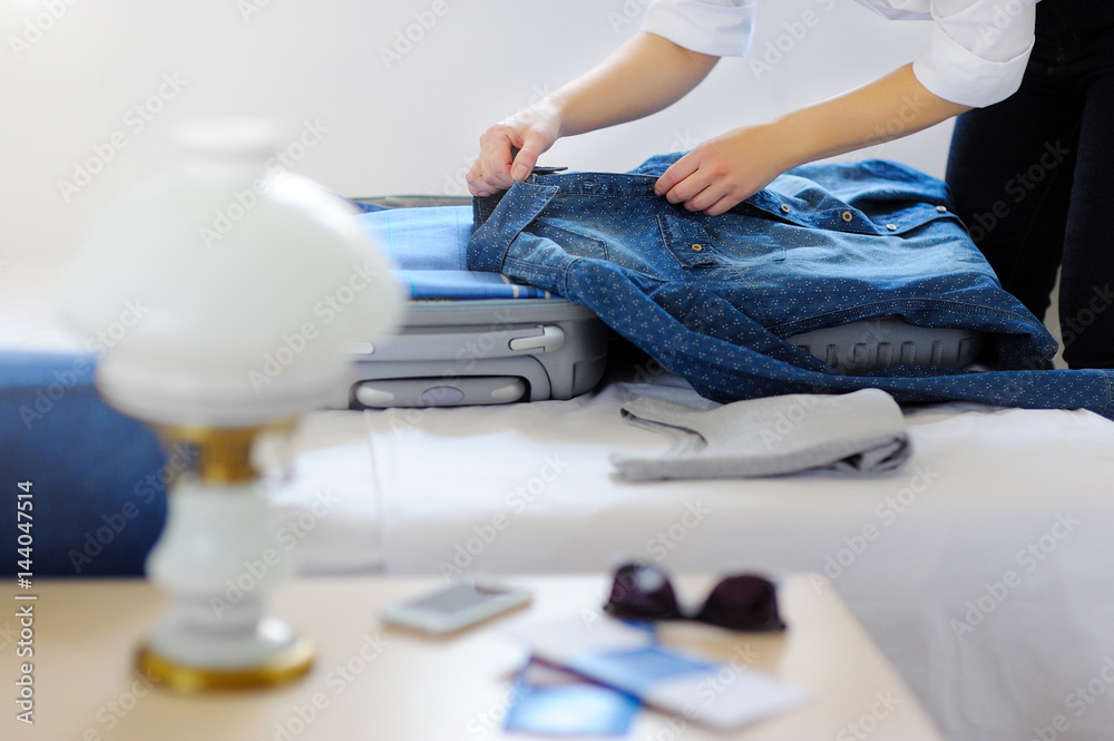 Fototapeta premium Close-up of female hands pack a suitcase. The journey begins!