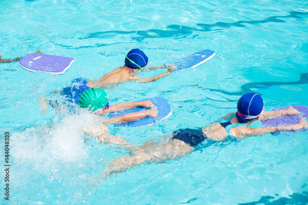 Little swimmers with kickboards swimming in pool