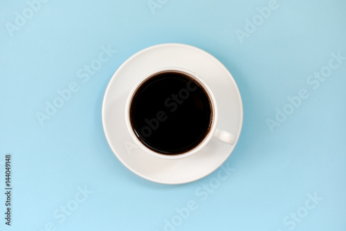 Black natural coffee in white cup over blue background. 