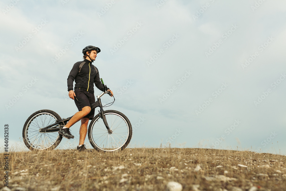 Man on bicycle standing on hill Man on bicycle standing on hill