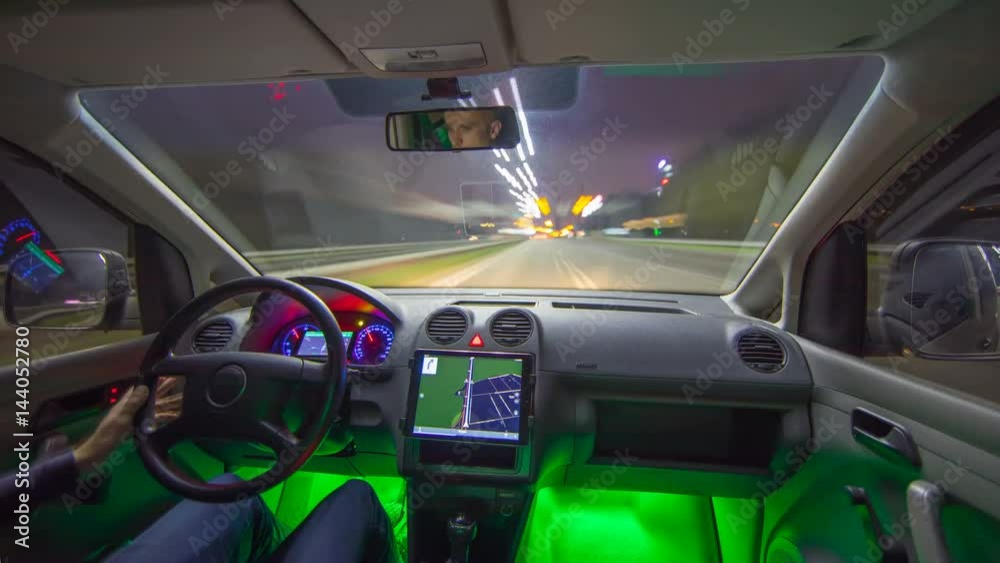 The man drive a car in the night city with a navigator. Inside view. Hyperlapse. Wide angle