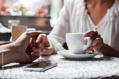 Young couple holding hands at the cafe, closeup