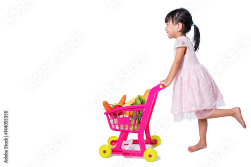 Asian Chinese little girl with shopping trolley full of vegetables