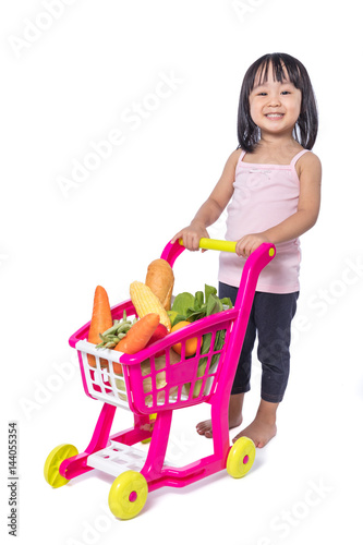 Asian Chinese little girl with shopping trolley full of vegetables