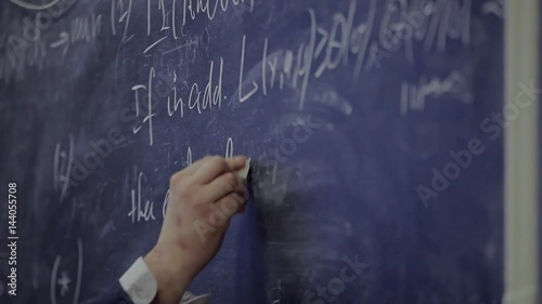 the hand writes on the blackboard a formula