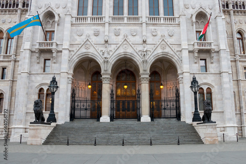 Hungarian parliament architecture details and national flags on facade over entrance, building located in Budapest, Hungary © aerial333