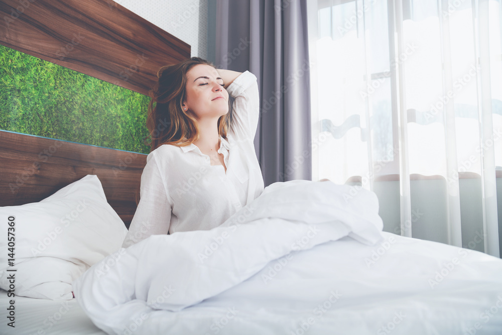 Pretty woman on bed in modern apartment smiling and stretching after wake up Pretty woman on bed in modern apartment smiling and stretching after wake up
