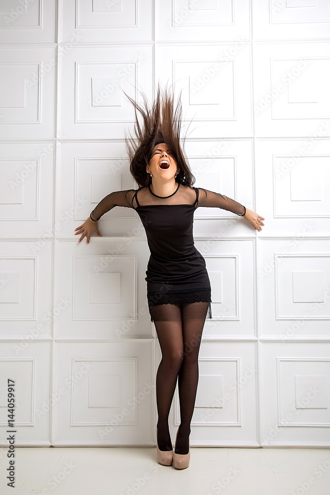 Beautiful girl model with flying the wind hair. A brunette woman in a black dress