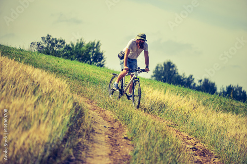 hipster man on a bicycle in the field