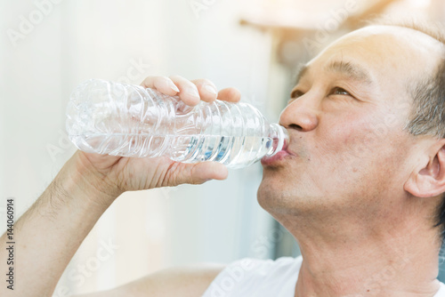 Fotografie Asian senior man drinking water at a gym