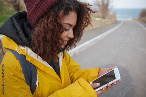 Woman near road using smartphone photo