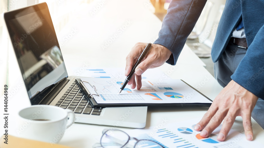 Business man working at office with laptop, tablet and graph data documents on his desk Business man working at office with laptop, tablet and graph data documents on his desk