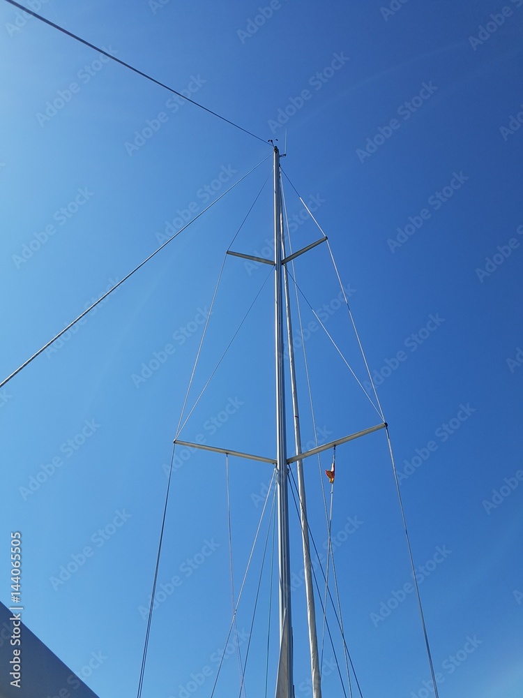 Masts of yachts against the blue sky and clouds