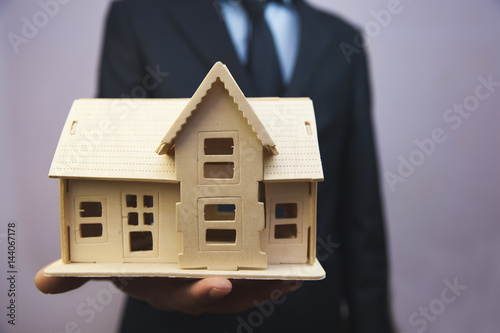 businessman hand wooden house model