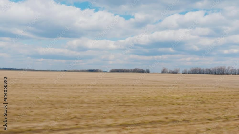 View from the window of a fast-moving car. Field early spring - plowed land and blue sky with clouds. Agricultural land. POV 3 axis stabilized video View from the window of a fast-moving car. Field early spring - plowed land and blue sky with clouds. Agricultural land. POV 3 axis stabilized video