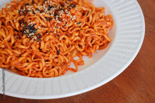 Spicy noodles sprinkle sesame seeds and seaweed on a wooden background.