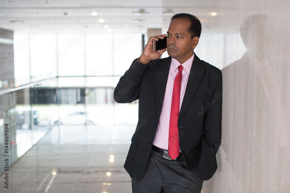 Serious Indian businessman talking on mobile phone Serious Indian businessman talking on mobile phone
