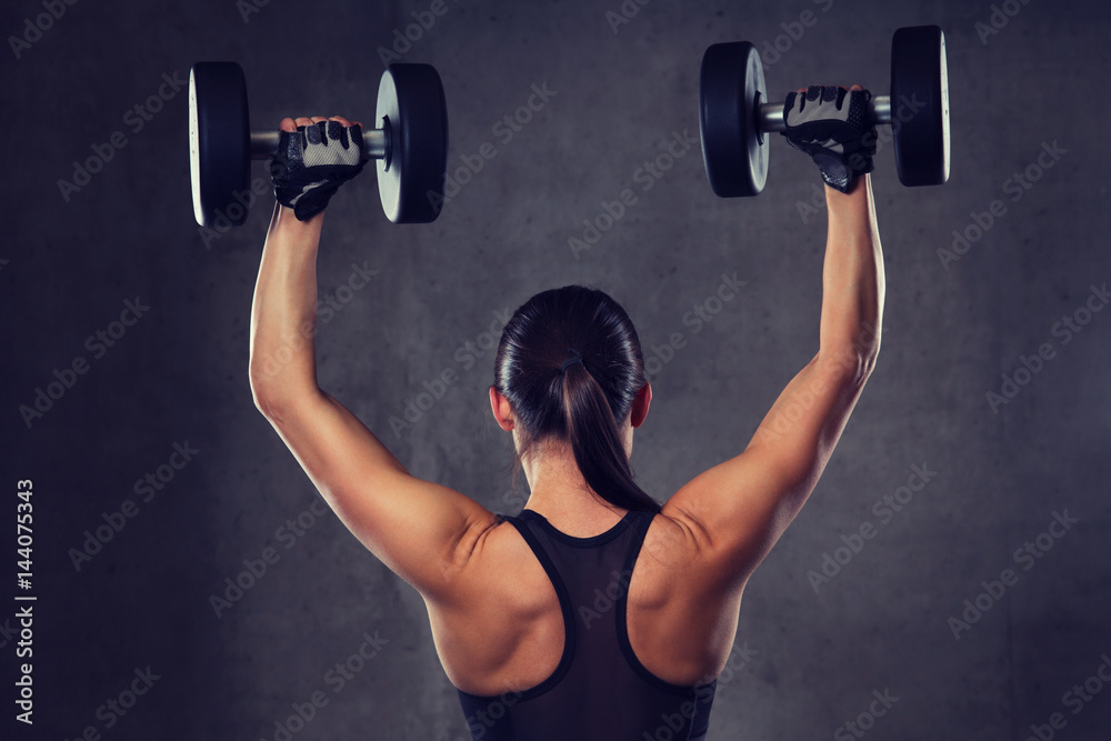 young woman flexing muscles with dumbbells in gym young woman flexing muscles with dumbbells in gym