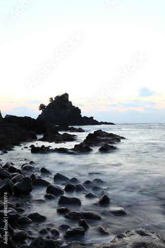 Sunrise and morning light on pacific ocean beach with rocks and water photo