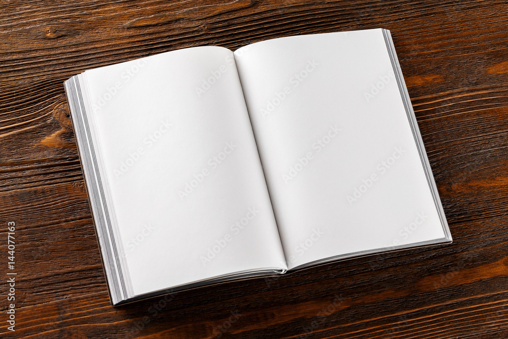 Fototapeta premium Mockup of opened book with blank pages at wooden table background.