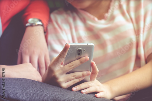 Woman hand using smart phone while sitting on sofa with her friend in casual lifestyle, vintage tone background, woman on phone concept