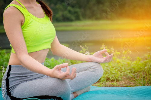 young woman sitting Yoga near river. Concept of healthy lifestyle and relaxation.