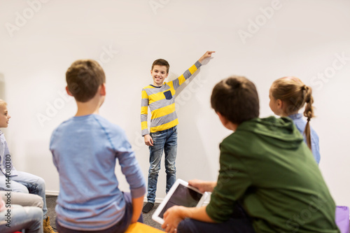 happy student boy showing something at white wall