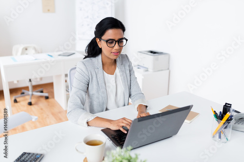 happy smiling businesswoman with laptop at office