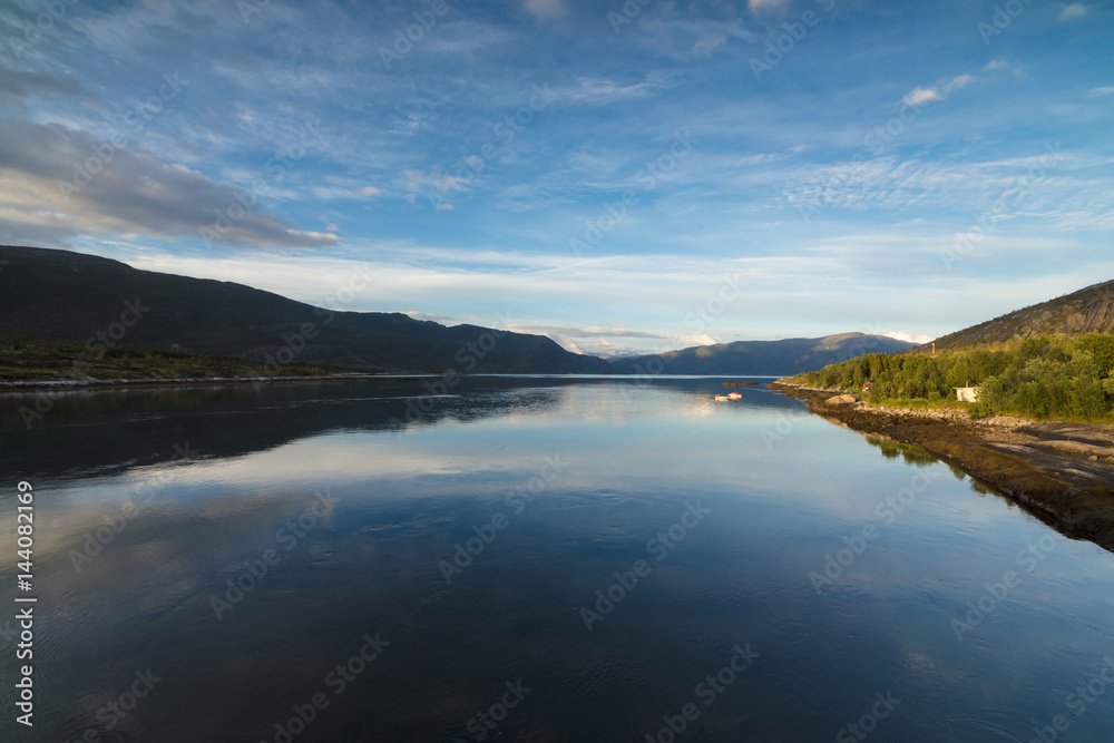 Light of the midnight sun illuminates the clear water of blue sea and green woods, Anepollen Fjord, Nordland Light of the midnight sun illuminates the clear water of blue sea and green woods, Anepollen Fjord, Nordland